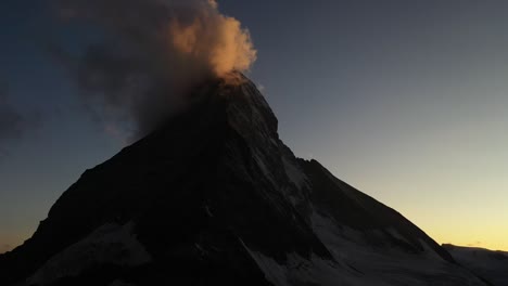 Slow-aerial-shot-moving-backwards,-facing-Matterhorn,-Switzerland-during-a-colorful-and-harmonious-sunrise