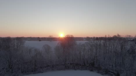 Rise-Over-Snow-covered-Trees-and-Field-to-Reveal-the-Sunrise-on-the-Horizon