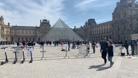 The-world-famous-glass-pyramid-of-the-Louvre-Museum-in-Paris,-France,-surrounded-by-tourists