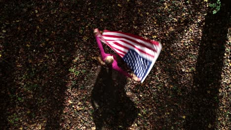 Mirando-Hacia-Abajo-Mientras-Una-Mujer-Gira-Y-Agita-Una-Bandera-Estadounidense-En-Un-Bosque