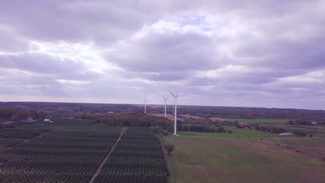 Aerial-footage-of-drone-moving-forward-towards-wind-farm-with-giant-wind-turbines-spinning-creating-renewable-energy