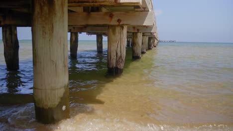 A-close-up-shot-of-the-wooden-pylons-underneath-a-pier-in-a-calm-bay-in-Australia