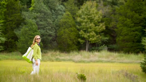 Cinemagraph-of-a-pretty-woman-walking-in-a-grassland-meadow-set-against-a-mature-forest