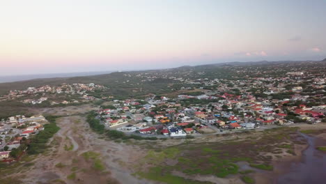 Houses-in-Noord,-Aruba-during-sunset-with-the-Caribbean-Sea-in-the-background