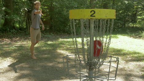 Man-Scores-a-Basket-in-a-Round-of-Disc-Golf-in-the-Woods-and-Celebrates-in-Slow-Motion