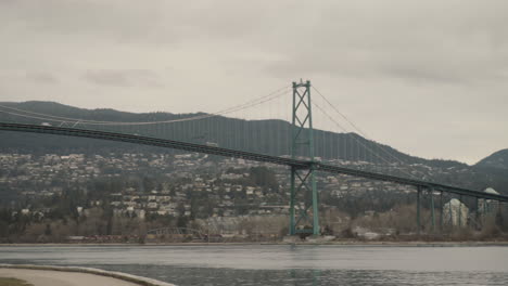 Wide-panning-shot-of-Lions-Gate-bridge-and-man-running-in-Stanley-park