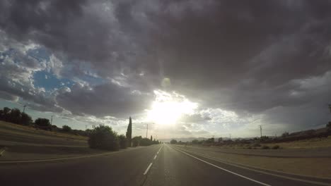 Timelapse-driving-towards-morning-sun-with-storm-clouds-above-in-California