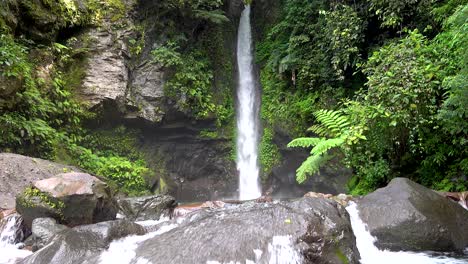 Wasserfall-Umgeben-Von-üppiger-Grüner-Vegetation,-Großen-Felsen-Und-Felsbrocken-In-Einem-Aktuellen-Inselregenwald