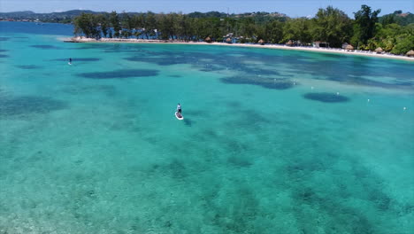 Vista-Aérea-De-Personas-Haciendo-Paddleboarding-Cerca-De-La-Playa-De-Un-Resort-En-El-Mar-Caribe-Hondureño