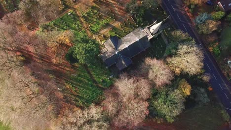 Birds-eye-view-above-British-countryside-rural-church---autumn-colours-on-trees-during-sunrise