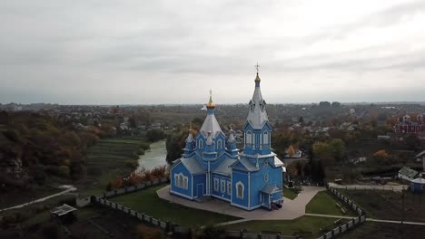 Drone-view-of-a-wooden,-blue-church-in-Ukraine