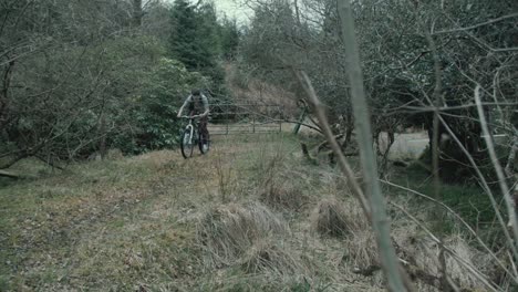 Filmmaker-cycles-within-forest-with-backpack-and-tripod