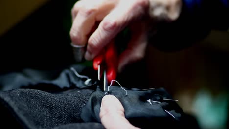 Closeup-Working-Seamstress-professional-cutting-cloth-threads-with-scissors
