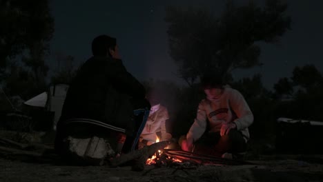 Refugee-sits-around-fire-on-cold-night-with-friends-to-keep-warm-Time-Lapse