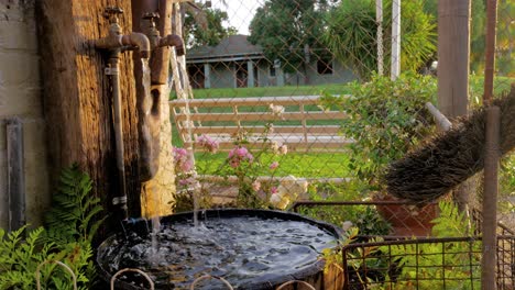 Water-feature-with-old-taps-and-water-falling-into-pool-of-half-wine-barrel