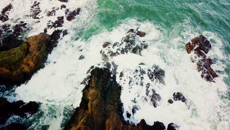 Aerial-shot-of-waves-crashing-against-rocks-revealing-ocean-horizon