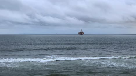 4k-60p,-Offshore-oil-rig-at-dusk-with-a-cloudy-sky-and-waves-rolling-in