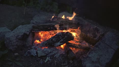 Close-up-of-campfire-and-stone-fireplace,-dolly-shot,-evening-colors