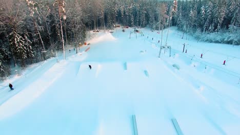 Tracking-Luftaufnahme-Eines-Snowboarders,-Der-In-Einem-Funpark-Einen-360-Grad-Sprung-Macht