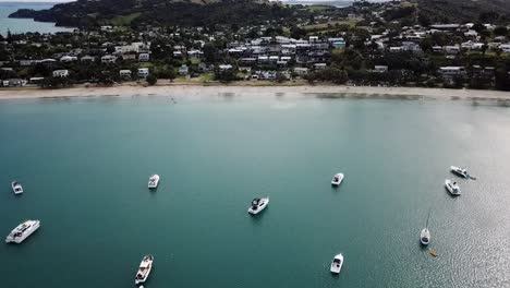 Aerial-view-of-the-town,-beach-and-bay-full-of-boats-at-Waiheke-island,-New-Zealand