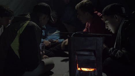 Refugees-playing-cards-around-stove-inside-makeshift-tent