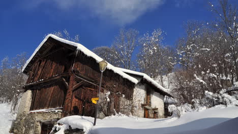 Time-lapse-of-an-old-wooden-chalet---barn-in-the-French-Alps-with-clouds-passing-by-on-a-blue-sky