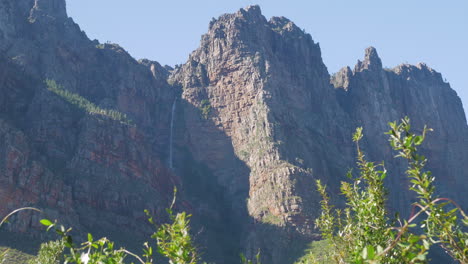 Waterfall-in-shade-of-mountain,-zoomed-in-shot-of-sandstone-mountains