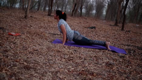 Mujer-Joven-Haciendo-Yoga-En-Un-Parque-Cerca-Del-Río-Durante-La-Mañana,-Destello-De-Lente-Y-Hermoso-Fondo-De-Vista