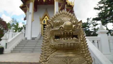 Eine-Steinerne-Löwenstatue-Steht-Vor-Dem-Versteckten-Thailändischen-Buddhistischen-Tempel