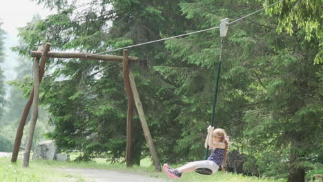 Little-girl-with-red-hair-has-fun-on-a-pulley-in-the-Italian-Alps,-slow-motion