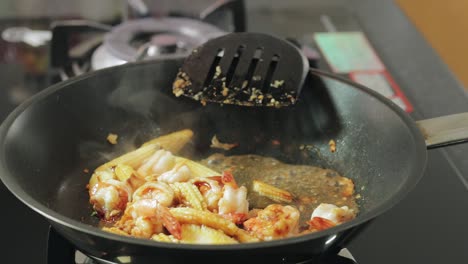 Woman-is-adding-water-to-frying-shrimps-with-chili-and-garlic-in-a-hot-frying-pan
