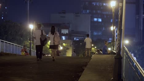 Pareja-De-Estudiantes-En-Uniforme-Caminando-Sobre-Un-Puente-Por-La-Noche
