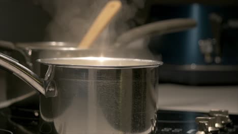 Close-up-of-two-pans-simmering-on-a-cooktop-with-steam-rising