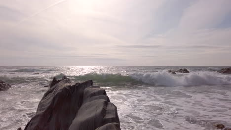 Left-to-Right-Pan-of-Waves-Breaking-Against-a-Rocky-Cove-on-a-Summer’s-Evening