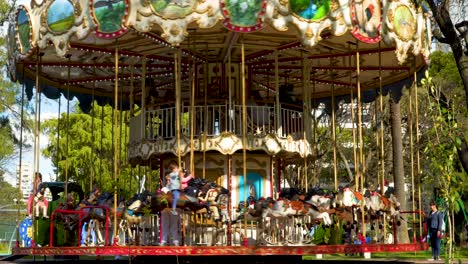 Kids-having-fun-riding-horses-in-a-classic-merry-go-round-spinning-in-a-park