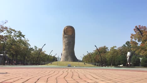People-take-a-stroll-near-a-big-sculpture-at-Olympic-Park,-Oryun-dong,-Songpa-gu,-Seoul,-South-Korea