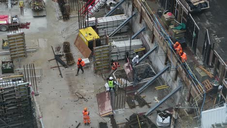 Construction-Workers-Hammering-Side-Of-Skip-At-Nine-Millbank-Place,-Westminster