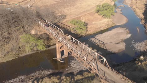 aerial-locked-off-shot-of-a-car-crossing-an-old-steel-bridge