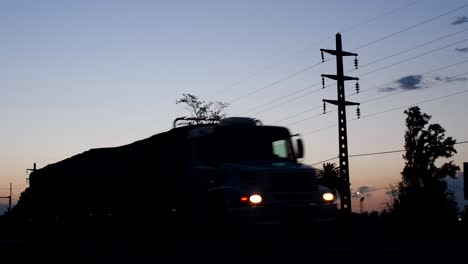 A-truck-and-a-car-pass-by-on-a-route-at-dusk