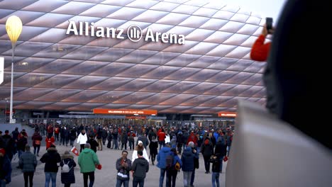 Fans-walking-to-Allianz-Arena,-home-stadium-of-famous-german-football-club-FC-Bayern-München-to-see-a-soccer-match