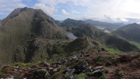 A-group-of-hikers-are-walking-down-the-trail-from-the-top-of-mountain-Mannen-at-Haukland-beach-in-Lofoten,-Norway