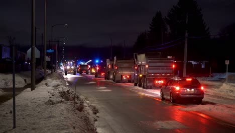 A-convoy-of-dump-trucks-waiting-to-load-up-snow-during-city-snow-removal-at-night