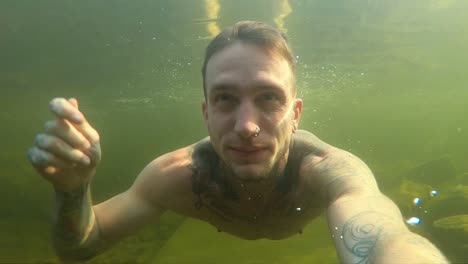 A-young-man-films-himself-with-an-action-camera-as-he-swims-through-the-dark,-gloomy-and-murky-the-cold-Norwegian-water