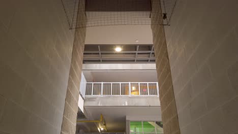 HVAC-system-in-ceiling-of-hallway-in-underground-parking-garage-in-city-moving-towards-opening-and-stairs-to-other-levels