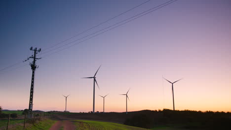 Dramatische-Sonnenuntergangssilhouette-Von-Windkraftanlagen-Und-Stromleitungen,-Breit