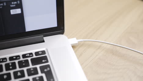Nahansicht-Des-Weißen-USB-Kabels,-Das-In-Den-Laptop-Ein--Und-Ausgesteckt-Wird