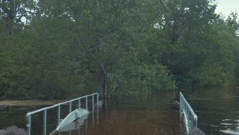 Crossing-flooded-walk-bridge-along-river-side-walk