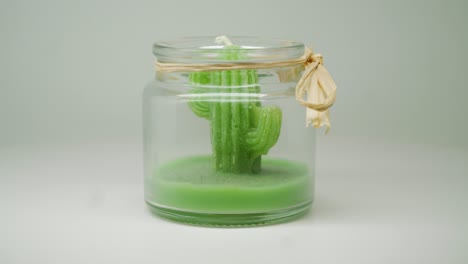 A-Green-Cactus-Wax-Candle-Inside-A-Clear-Jar-Slowly-Moving-On-A-Circular-Motion---Close-Up-Shot