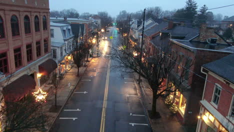 Christmas-lights-and-traditional-seasonal-decoration-in-the-streets-of-a-small-American-town-in-Pennsylvania,-illuminated-storefornts-in-Lititz,-PA,-aerial-view