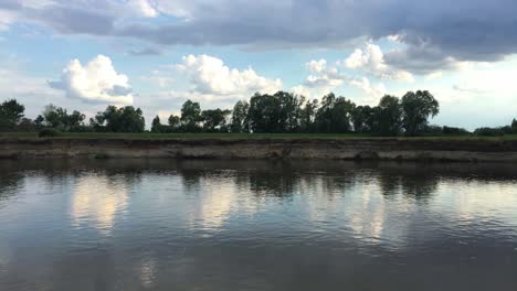 timelapse-over-warta-river-with-clouds-moving-fast-and-tree-green-field-and-water-reflection